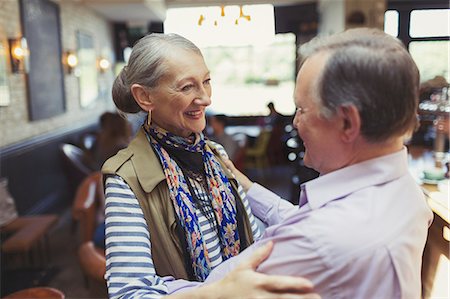 senior couple standing talking - Affectionate senior couple hugging in bar Stock Photo - Premium Royalty-Free, Code: 6113-08882641