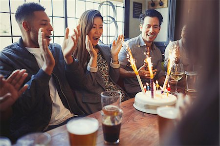 simsearch:6113-08882616,k - Friends cheering for woman celebrating birthday with fireworks cake at table in bar Foto de stock - Sin royalties Premium, Código: 6113-08882666