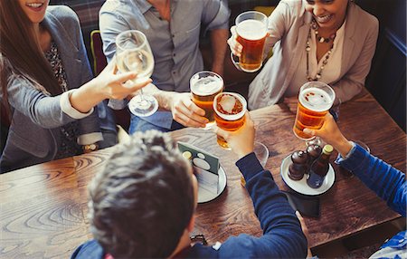 Overhead view friends celebrating, toasting beer and wine glasses at table in bar Stock Photo - Premium Royalty-Free, Code: 6113-08882670