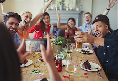 simsearch:640-08089023,k - Woman with camera phone photographing playful friends throwing confetti at restaurant table Stock Photo - Premium Royalty-Free, Code: 6113-08882691