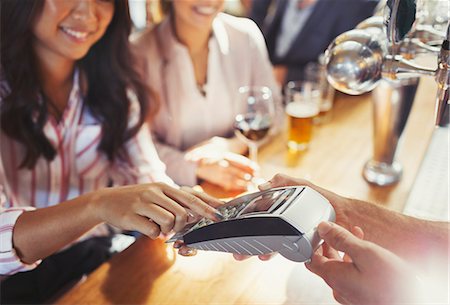 Woman paying bartender using credit card machine at bar Photographie de stock - Premium Libres de Droits, Code: 6113-08882622