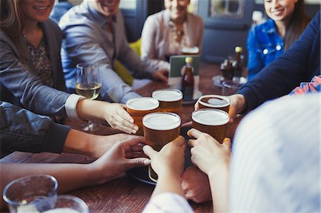 socializing bar pub - Friends reaching for beer glasses on bar table Stock Photo - Premium Royalty-Free, Code: 6113-08882639