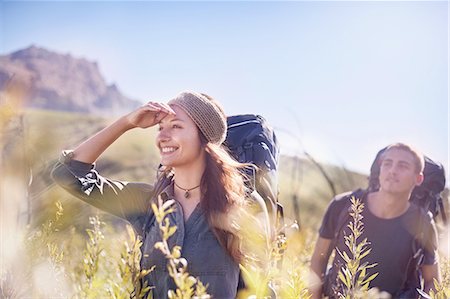 simsearch:6113-08743450,k - Smiling couple with backpacks hiking in sunny field Foto de stock - Royalty Free Premium, Número: 6113-08882767