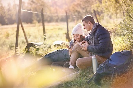 ecoturismo - Young couple hikers resting in sunny grass using cell phone and digital tablet Foto de stock - Sin royalties Premium, Código: 6113-08882770