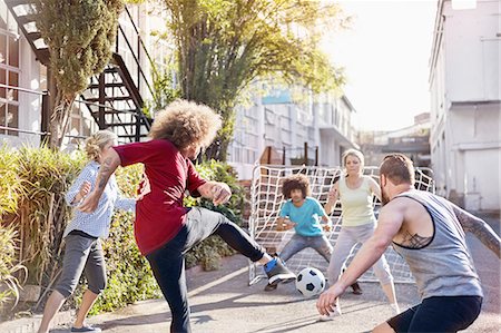 simsearch:6113-08882733,k - Friends playing soccer in sunny summer street Stock Photo - Premium Royalty-Free, Code: 6113-08882704