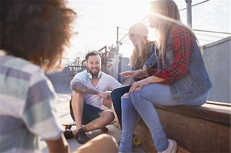 simsearch:6113-08882728,k - Friends with skateboards hanging out and talking at sunny skate park Foto de stock - Royalty Free Premium, Número: 6113-08882717