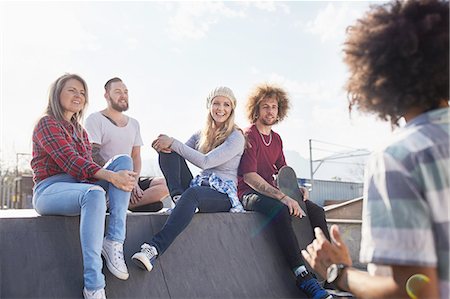 simsearch:6113-08882728,k - Friends hanging out and talking at sunny skate park Foto de stock - Royalty Free Premium, Número: 6113-08882728