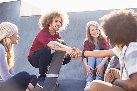 simsearch:6113-08882733,k - Friends with skateboards handshaking at sunny skate park Stock Photo - Premium Royalty-Free, Code: 6113-08882735
