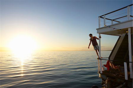 railing - Man leaning on summer houseboat railing over sunset ocean Stock Photo - Premium Royalty-Free, Code: 6113-08805285