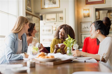 eating brunch - Smiling women drinking coffee and talking at restaurant table Stock Photo - Premium Royalty-Free, Code: 6113-08805353
