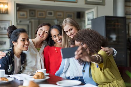 simsearch:6113-08805305,k - Smiling women friends taking selfie at restaurant table Fotografie stock - Premium Royalty-Free, Codice: 6113-08805316