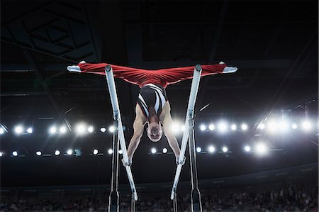 fit (tight clothes) - Male gymnast performing upside-down splits on parallel bars in arena Stock Photo - Premium Royalty-Free, Code: 6113-08805443