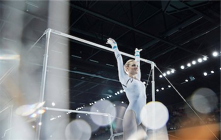 simsearch:632-06118243,k - Female gymnast with arms raised below uneven bars in arena Stock Photo - Premium Royalty-Free, Code: 6113-08805453