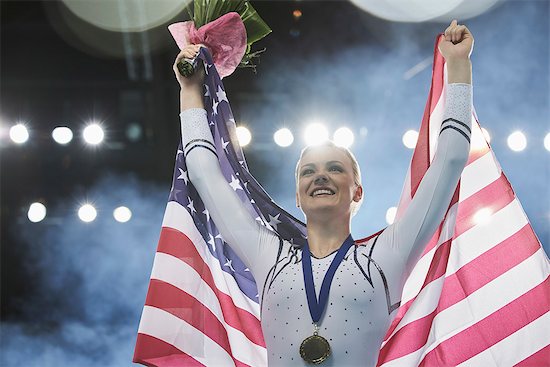 Enthusiastic female gymnast celebrating victory holding American flag on winners podium Stock Photo - Premium Royalty-Free, Image code: 6113-08805450