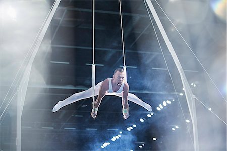 simsearch:632-05760558,k - Male gymnast performing on gymnastics rings in arena Foto de stock - Sin royalties Premium, Código: 6113-08805464