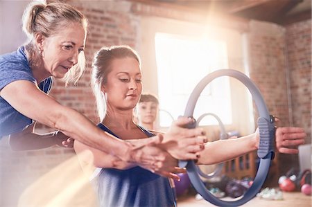 simsearch:6113-08805404,k - Fitness instructor helping young woman using pilates ring in exercise class gym studio Foto de stock - Royalty Free Premium, Número: 6113-08805487