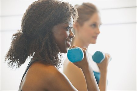 simsearch:6113-08805366,k - Smiling woman doing biceps curls in exercise class gym studio Stock Photo - Premium Royalty-Free, Code: 6113-08805417