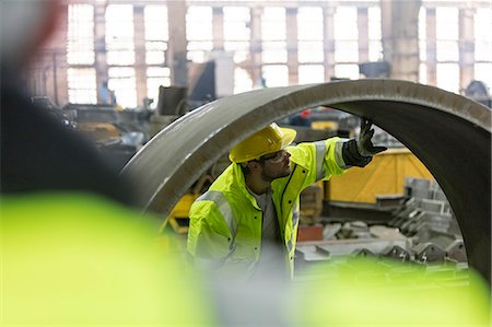 Steel worker examining pipe in factory Stock Photo - Premium Royalty-Free, Code: 6113-08805544