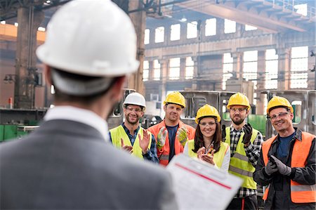 successful businessman standing photo - Steel workers clapping for manager in meeting in factory Stock Photo - Premium Royalty-Free, Code: 6113-08805590