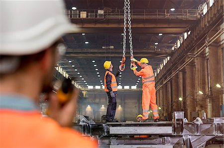 Steel workers adjusting crane hooks in factory Stock Photo - Premium Royalty-Free, Code: 6113-08805596