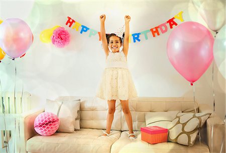 simsearch:614-08868116,k - Portrait confident girl with arms raised on sofa at birthday party Stock Photo - Premium Royalty-Free, Code: 6113-08805653