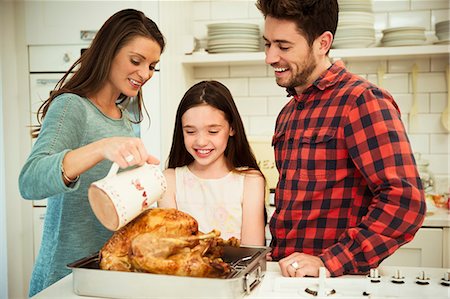Family preparing Christmas dinner turkey in kitchen Photographie de stock - Premium Libres de Droits, Code: 6113-08805694