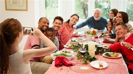 simsearch:6113-08805684,k - Girl with camera phone photographing multi-ethnic family at Christmas dinner table Photographie de stock - Premium Libres de Droits, Code: 6113-08805635