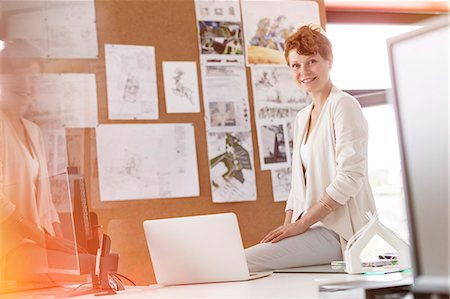 simsearch:6124-08907892,k - Portrait smiling female designer working at laptop in office Stock Photo - Premium Royalty-Free, Code: 6113-08805745