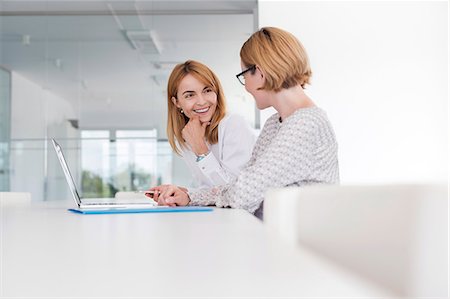 simsearch:6113-08805771,k - Businesswomen working at laptop in conference room Foto de stock - Sin royalties Premium, Código: 6113-08805770