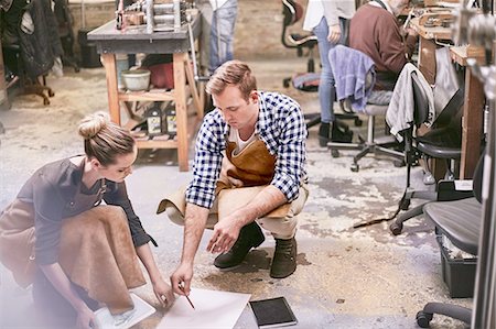 squatting man - Jewelers brainstorming with digital tablet and blueprint in workshop Stock Photo - Premium Royalty-Free, Code: 6113-08805736