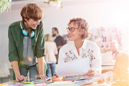 Smiling female design professionals reviewing proofs in office Stock Photo - Premium Royalty-Free, Code: 6113-08805873