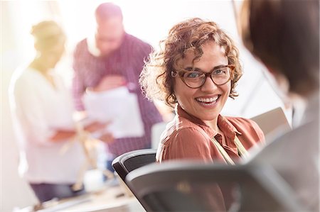 Smiling businesswoman listening to colleague in office Foto de stock - Sin royalties Premium, Código: 6113-08805878