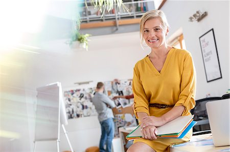 simsearch:6113-08805775,k - Portrait smiling female design professional leaning on office desk Foto de stock - Sin royalties Premium, Código: 6113-08805897