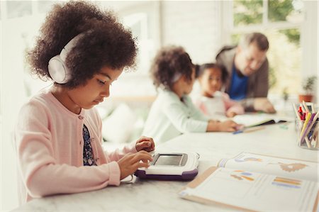 early childhood education - Girl with headphones using digital tablet doing homework at table Stock Photo - Premium Royalty-Free, Code: 6113-08943585