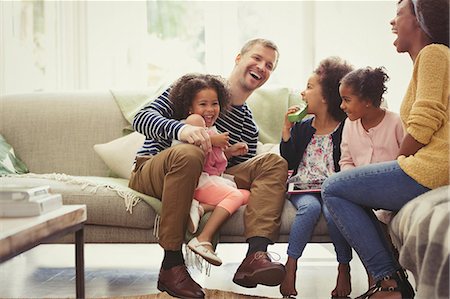 Multi-ethnic young family laughing on sofa Foto de stock - Sin royalties Premium, Código: 6113-08943666