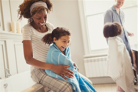 Pregnant mother wrapping towel around daughter after bath in bathroom Foto de stock - Sin royalties Premium, Código: 6113-08943669