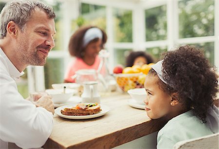 funny family breakfast - Multi-ethnic father and daughter playing staring game at kitchen table Stock Photo - Premium Royalty-Free, Code: 6113-08943670