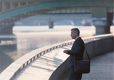 simsearch:6108-06166081,k - Businessman with briefcase and cell phone at urban waterfront Stock Photo - Premium Royalty-Free, Code: 6113-08943695