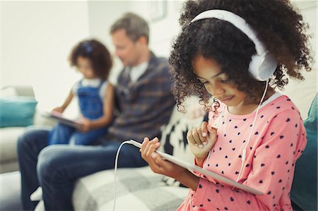 simsearch:632-08545827,k - Girl with headphones using digital tablet on sofa Fotografie stock - Premium Royalty-Free, Codice: 6113-08943624