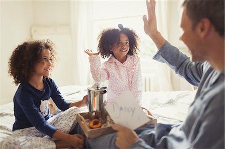 person reading greeting card - Father receiving Father's Day card from daughters and high-fiving on bed Stock Photo - Premium Royalty-Free, Code: 6113-08943625