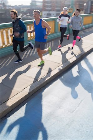 runner - Runners running on sunny urban bridge sidewalk Stock Photo - Premium Royalty-Free, Code: 6113-08943776