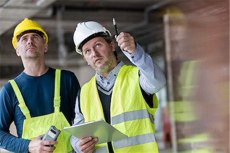 Male foreman and engineer with clipboard looking up at construction site Photographie de stock - Premium Libres de Droits, Code: 6113-08943895