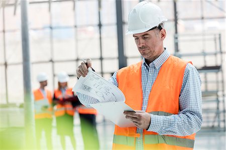 simsearch:6113-08321771,k - Male engineer reviewing blueprints on clipboard at construction site Foto de stock - Royalty Free Premium, Número: 6113-08943896