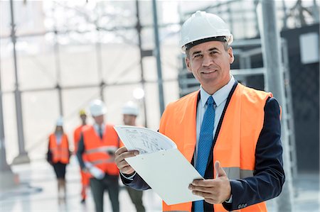 simsearch:6108-06168232,k - Portrait smiling businessman with clipboard at construction site Foto de stock - Royalty Free Premium, Número: 6113-08943925