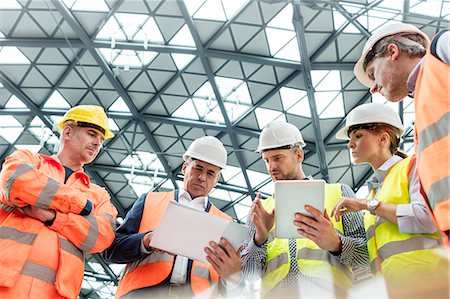 Foreman and construction workers using digital tablets in meeting at construction site Photographie de stock - Premium Libres de Droits, Code: 6113-08943938