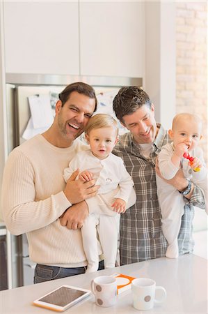 simsearch:6113-08947250,k - Portrait male gay parents holding baby sons in kitchen Fotografie stock - Premium Royalty-Free, Codice: 6113-08947252