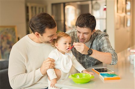 simsearch:6108-06907344,k - Male gay parents feeding baby son in kitchen Stock Photo - Premium Royalty-Free, Code: 6113-08947284