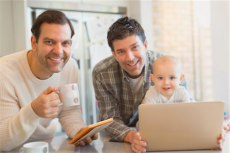 Portrait smiling male gay parents with baby son using digital tablet and laptop in kitchen Stockbilder - Premium RF Lizenzfrei, Bildnummer: 6113-08947286