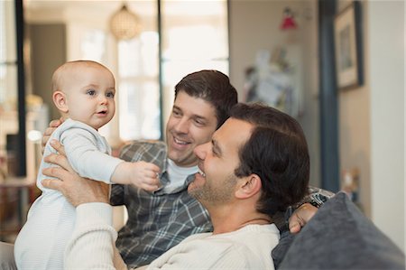 Male gay parents holding cute baby son on sofa Stock Photo - Premium Royalty-Free, Code: 6113-08947229