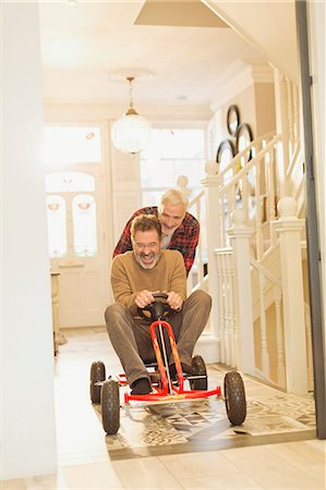 simsearch:600-03463202,k - Playful male gay couple playing with toy car in foyer corridor Foto de stock - Sin royalties Premium, Código: 6113-08947340